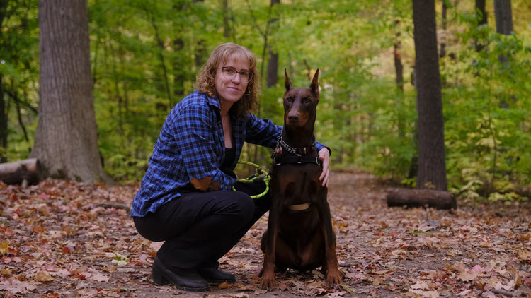Woman with a Doberman Pinscher in a forest setting