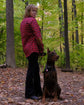 Person in a red plaid shirt standing with a dog in a forest