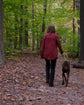 Person walking a dog on a path through a forest